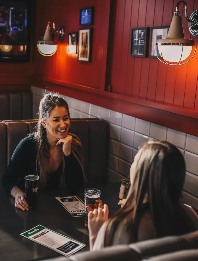 2 people sitting at Brewsters enjoying a beer and company